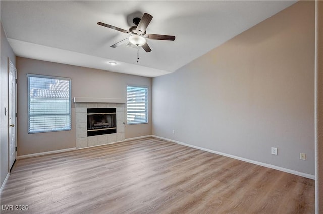 unfurnished living room with a tile fireplace, ceiling fan, and light hardwood / wood-style floors