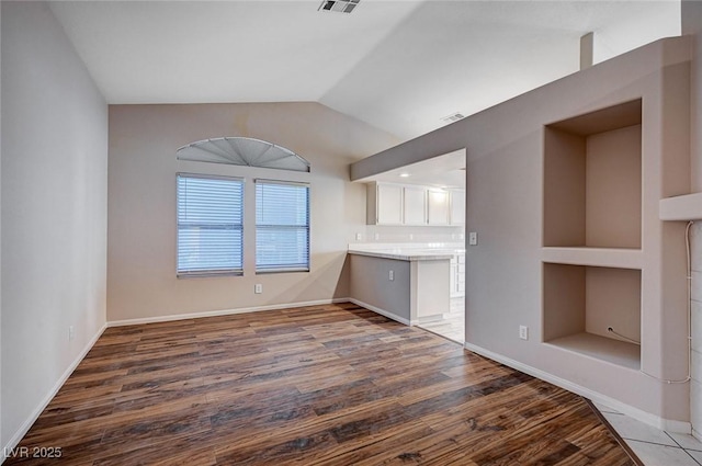 unfurnished living room with lofted ceiling and dark wood-type flooring