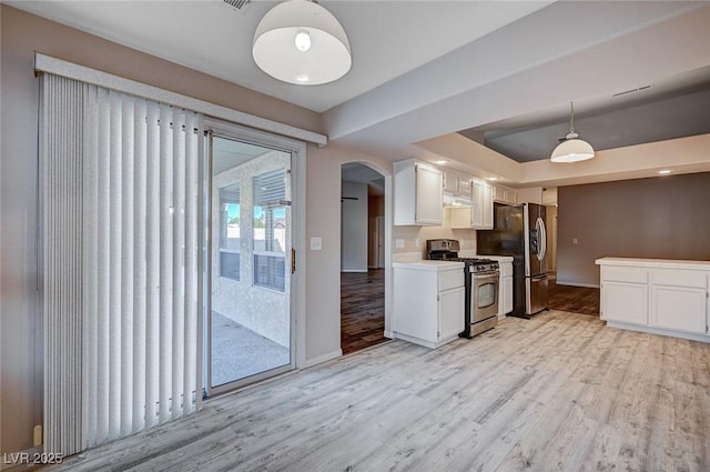 kitchen with hanging light fixtures, light hardwood / wood-style flooring, a tray ceiling, white cabinetry, and stainless steel appliances