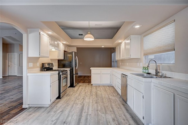 kitchen featuring stainless steel appliances, a raised ceiling, sink, decorative light fixtures, and white cabinets