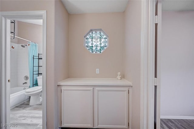 bathroom with shower / bath combination with curtain, wood-type flooring, and toilet