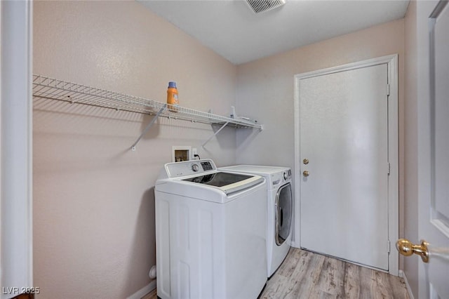 clothes washing area with light hardwood / wood-style flooring and washing machine and clothes dryer