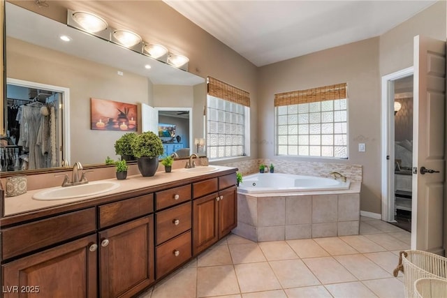 bathroom with tile patterned flooring, vanity, and a relaxing tiled tub