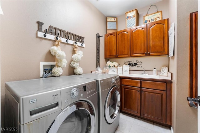 washroom with cabinets, light tile patterned flooring, washing machine and clothes dryer, and sink