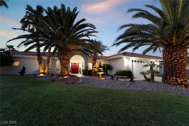 mediterranean / spanish-style house with a garage and a lawn