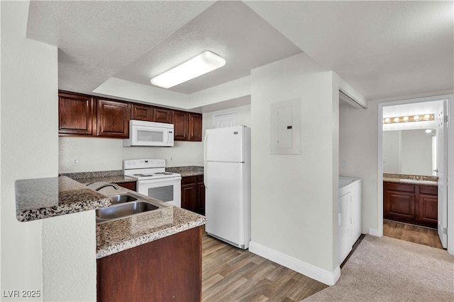 kitchen with dark brown cabinetry, stone counters, sink, white appliances, and light wood-type flooring