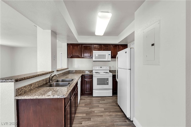 kitchen featuring sink, light stone counters, kitchen peninsula, electric panel, and white appliances