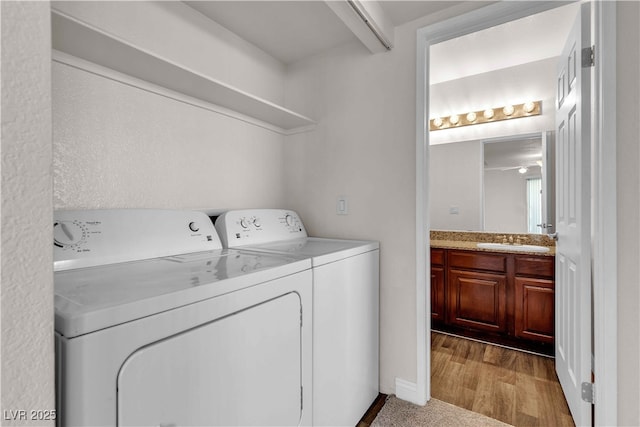 clothes washing area featuring washing machine and clothes dryer, sink, and hardwood / wood-style floors