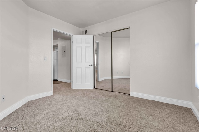 unfurnished bedroom with white refrigerator, carpet floors, and a closet