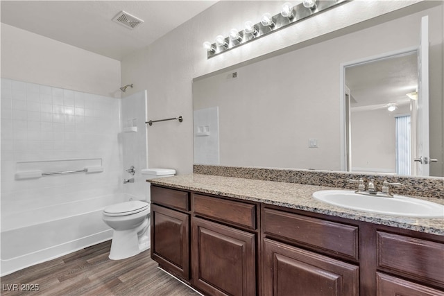 full bathroom featuring washtub / shower combination, wood-type flooring, vanity, and toilet