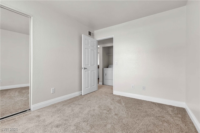 unfurnished bedroom featuring washer / clothes dryer and light colored carpet