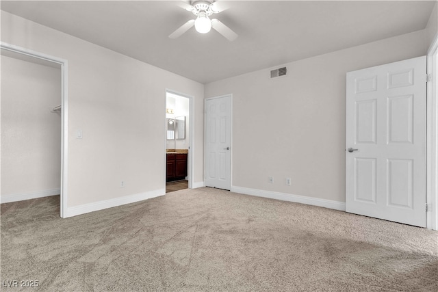 unfurnished bedroom with a walk in closet, ensuite bath, ceiling fan, carpet floors, and a closet