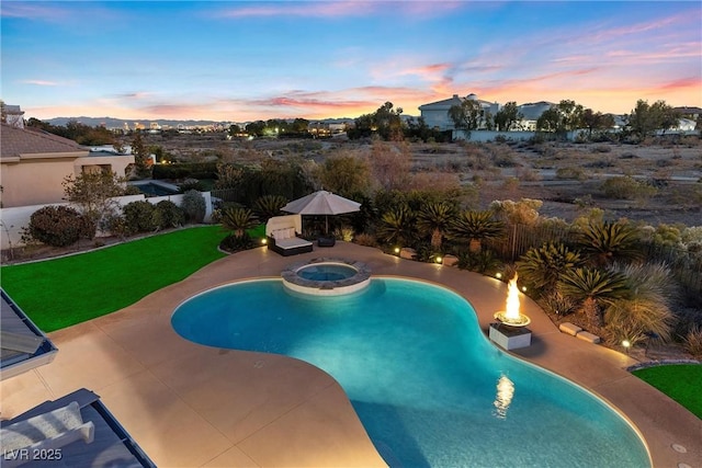 pool at dusk with an in ground hot tub, a yard, and a patio