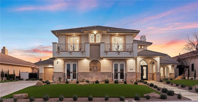 mediterranean / spanish home featuring french doors, a balcony, and a lawn