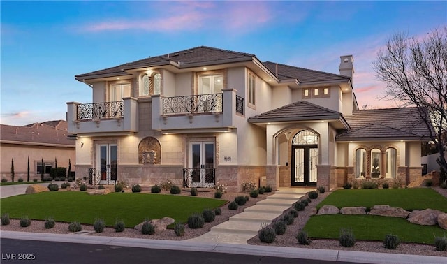 view of front of house featuring a yard, french doors, and a balcony