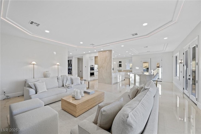 living room with a raised ceiling and french doors