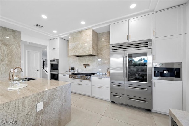 kitchen featuring white cabinets, stainless steel appliances, wall chimney range hood, and sink