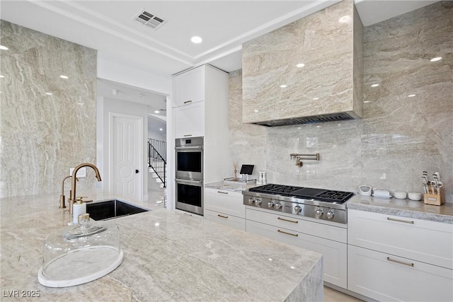 kitchen featuring white cabinets, stainless steel appliances, and light stone counters