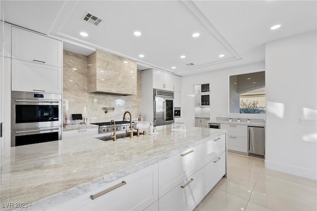 kitchen featuring white cabinetry, sink, stainless steel appliances, light stone counters, and light tile patterned flooring