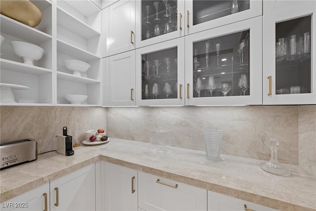 kitchen with white cabinets, light stone countertops, and tasteful backsplash