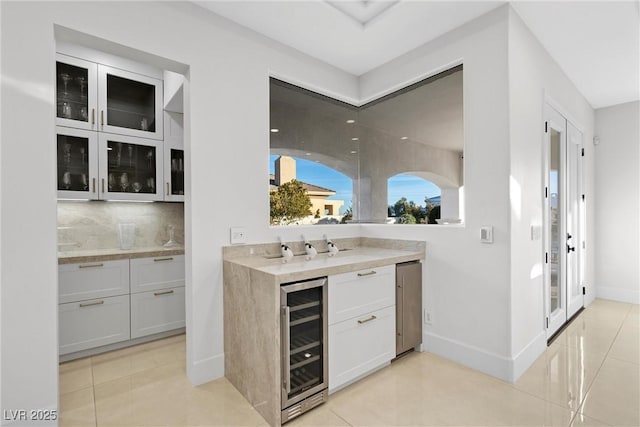 bar with light tile patterned floors, tasteful backsplash, white cabinetry, and beverage cooler