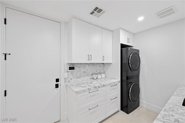 laundry room with cabinets and stacked washer and clothes dryer