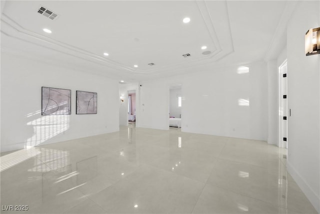 unfurnished room with a tray ceiling, crown molding, and light tile patterned flooring