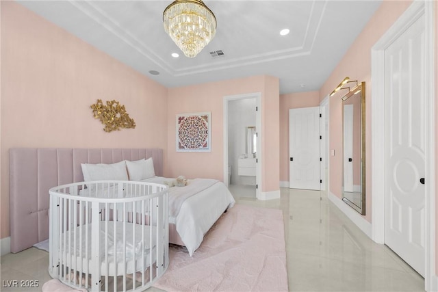 bedroom with light tile patterned floors, ensuite bathroom, a tray ceiling, and a notable chandelier