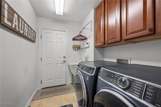 clothes washing area featuring washing machine and dryer, light tile patterned flooring, and cabinets