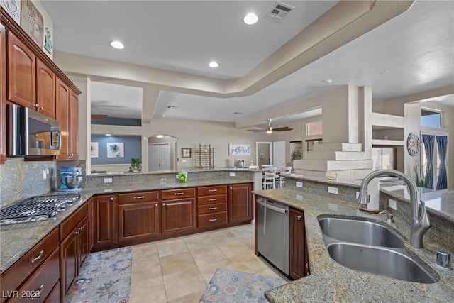 kitchen with decorative backsplash, sink, appliances with stainless steel finishes, light tile patterned floors, and light stone counters