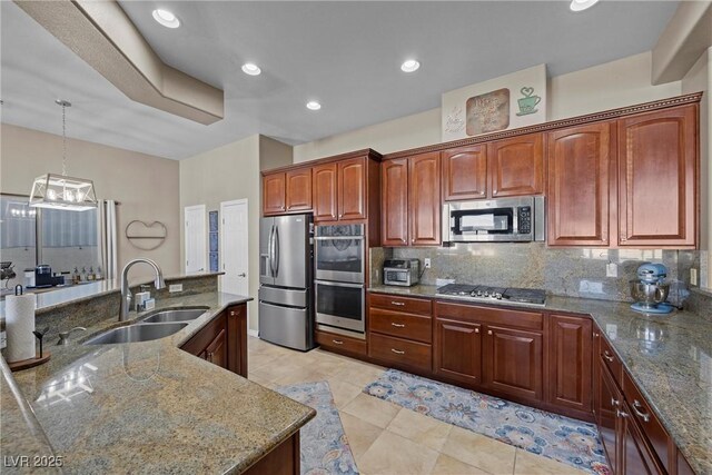 kitchen with light stone countertops, stainless steel appliances, decorative backsplash, sink, and hanging light fixtures