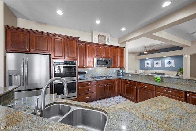 kitchen featuring appliances with stainless steel finishes, light stone counters, tasteful backsplash, and sink