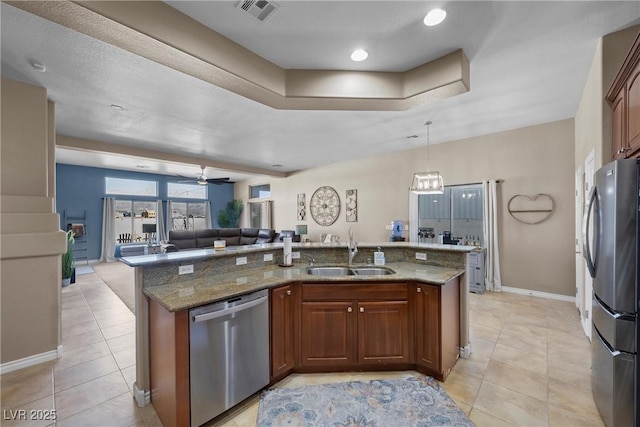 kitchen with sink, stone countertops, appliances with stainless steel finishes, and a kitchen island with sink