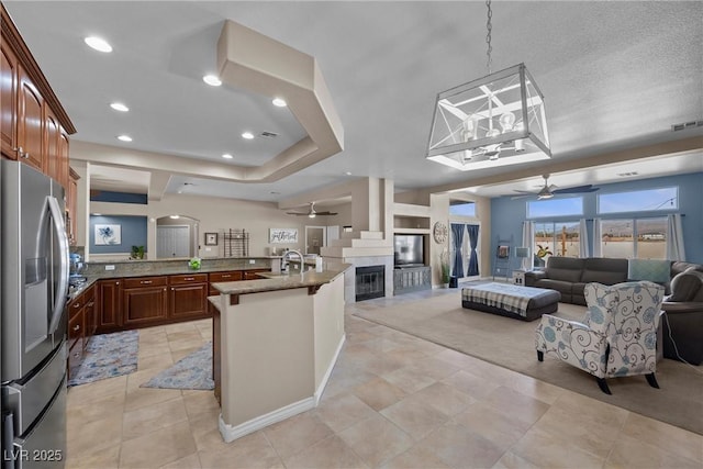 kitchen featuring ceiling fan, a breakfast bar, stainless steel refrigerator with ice dispenser, and sink