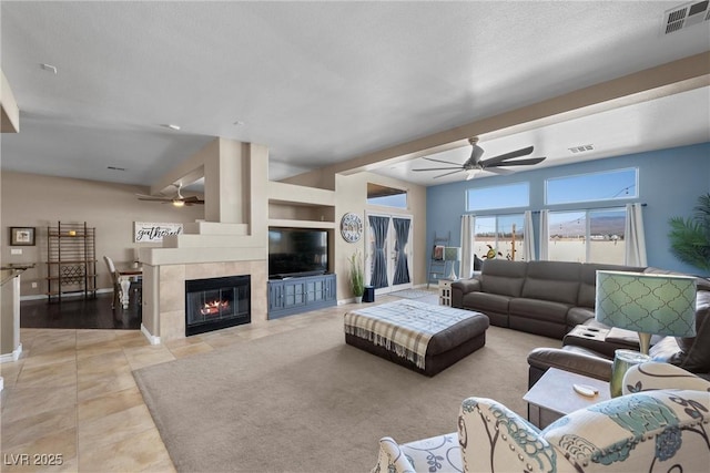 tiled living room featuring ceiling fan and a fireplace