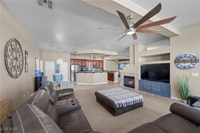 living room with ceiling fan, light colored carpet, and a tile fireplace