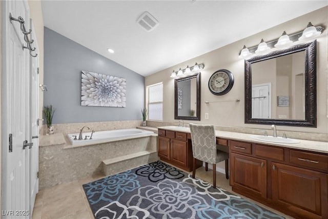 bathroom with vaulted ceiling, tile patterned floors, tiled bath, and vanity