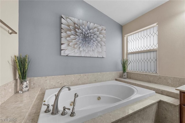 bathroom featuring tiled bath, lofted ceiling, and vanity