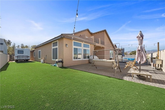 back of property featuring a patio area, a balcony, and a yard