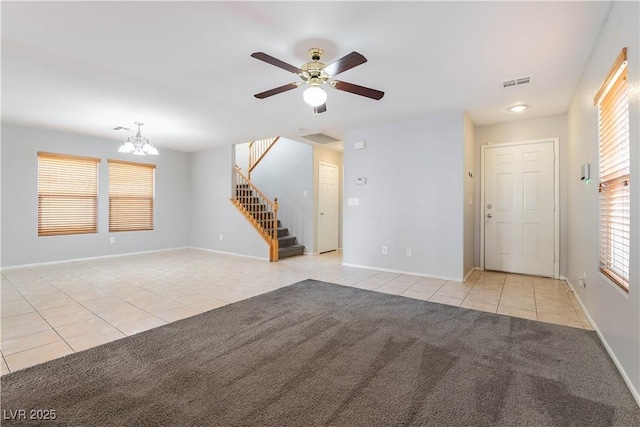 unfurnished living room with ceiling fan with notable chandelier, light tile patterned floors, and a wealth of natural light