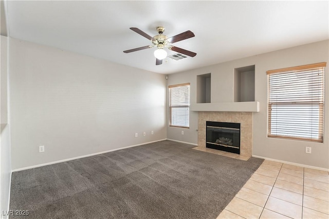 unfurnished living room with a tile fireplace, ceiling fan, plenty of natural light, and light tile patterned floors