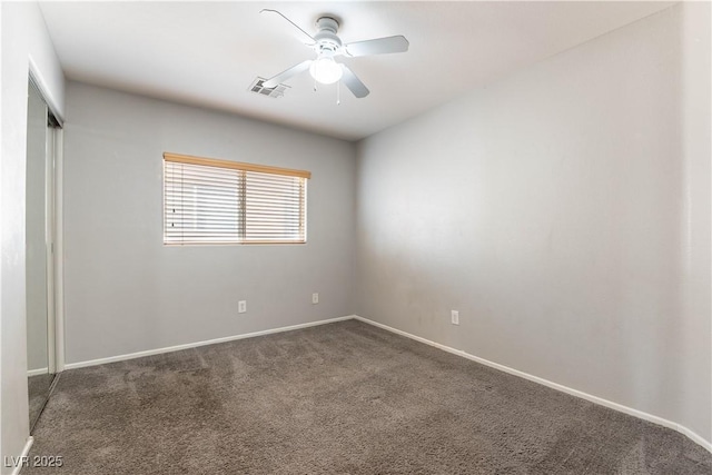 spare room with ceiling fan and dark carpet