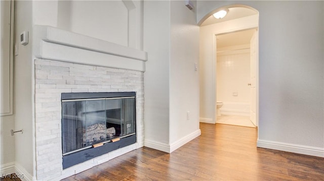 unfurnished living room with a fireplace, wood finished floors, and baseboards