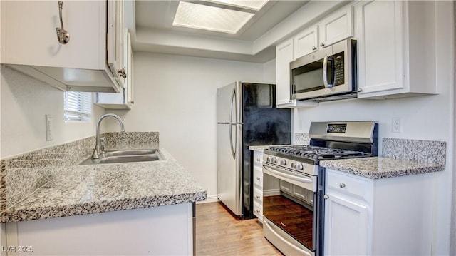 kitchen with light countertops, appliances with stainless steel finishes, light wood-style floors, white cabinetry, and a sink