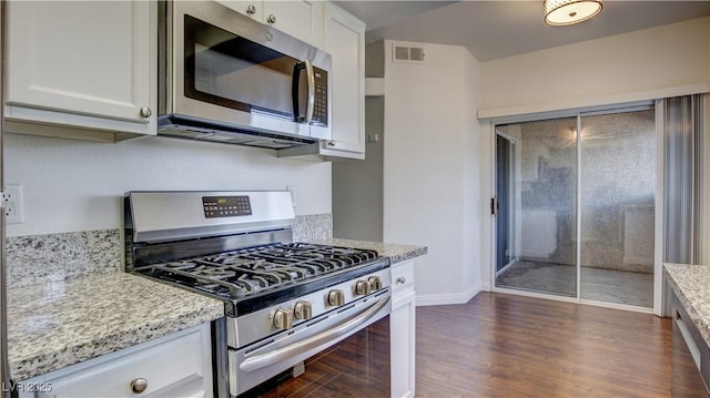 kitchen featuring visible vents, white cabinets, dark wood-type flooring, light stone countertops, and stainless steel appliances