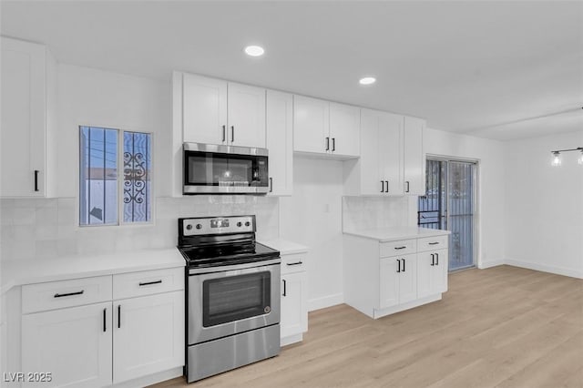 kitchen with decorative backsplash, white cabinets, stainless steel appliances, and light wood-type flooring