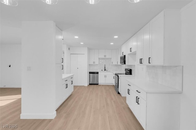 kitchen featuring appliances with stainless steel finishes, tasteful backsplash, sink, light hardwood / wood-style flooring, and white cabinetry