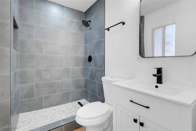 bathroom featuring vanity, toilet, and tiled shower