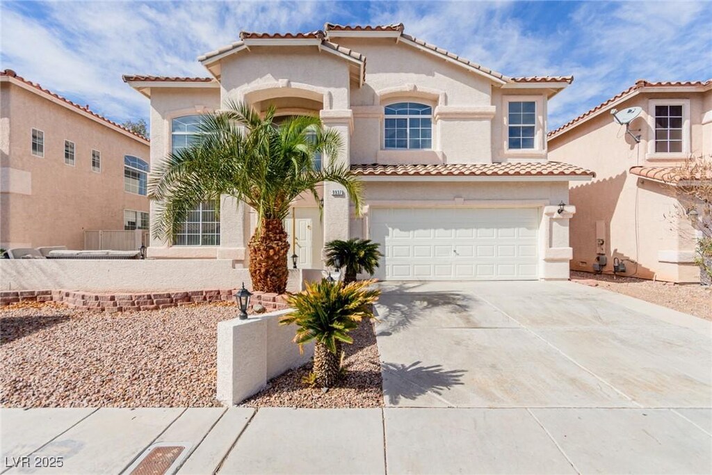 mediterranean / spanish-style home featuring a garage, driveway, and stucco siding