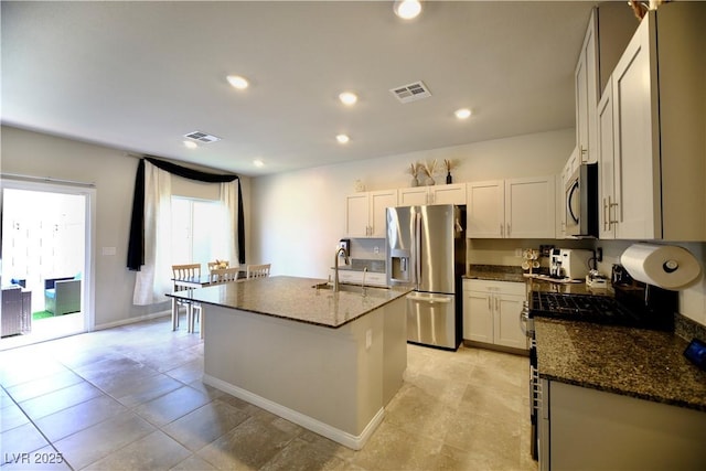 kitchen with sink, white cabinetry, stainless steel appliances, and a kitchen island with sink